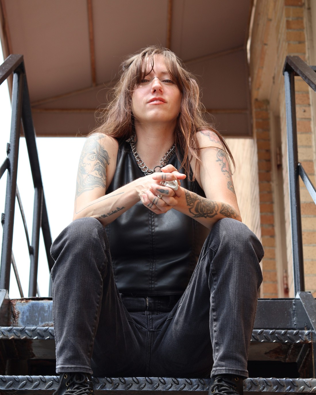 Bridgette seated on a steel fire escape, photographed from below