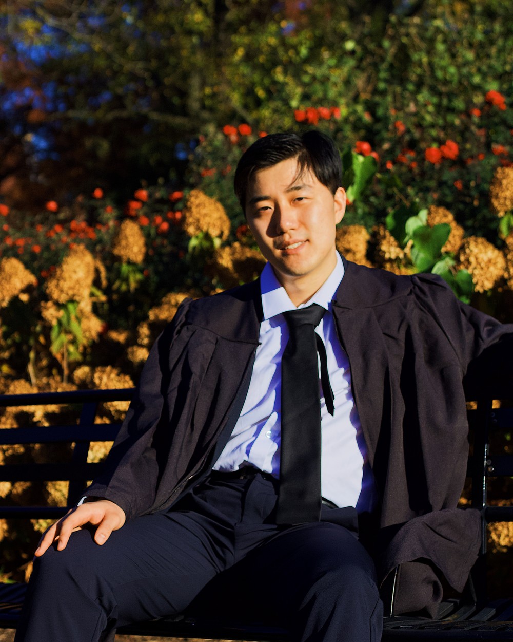 Graduate leaning against a brick colonnade, photographed by Anthony