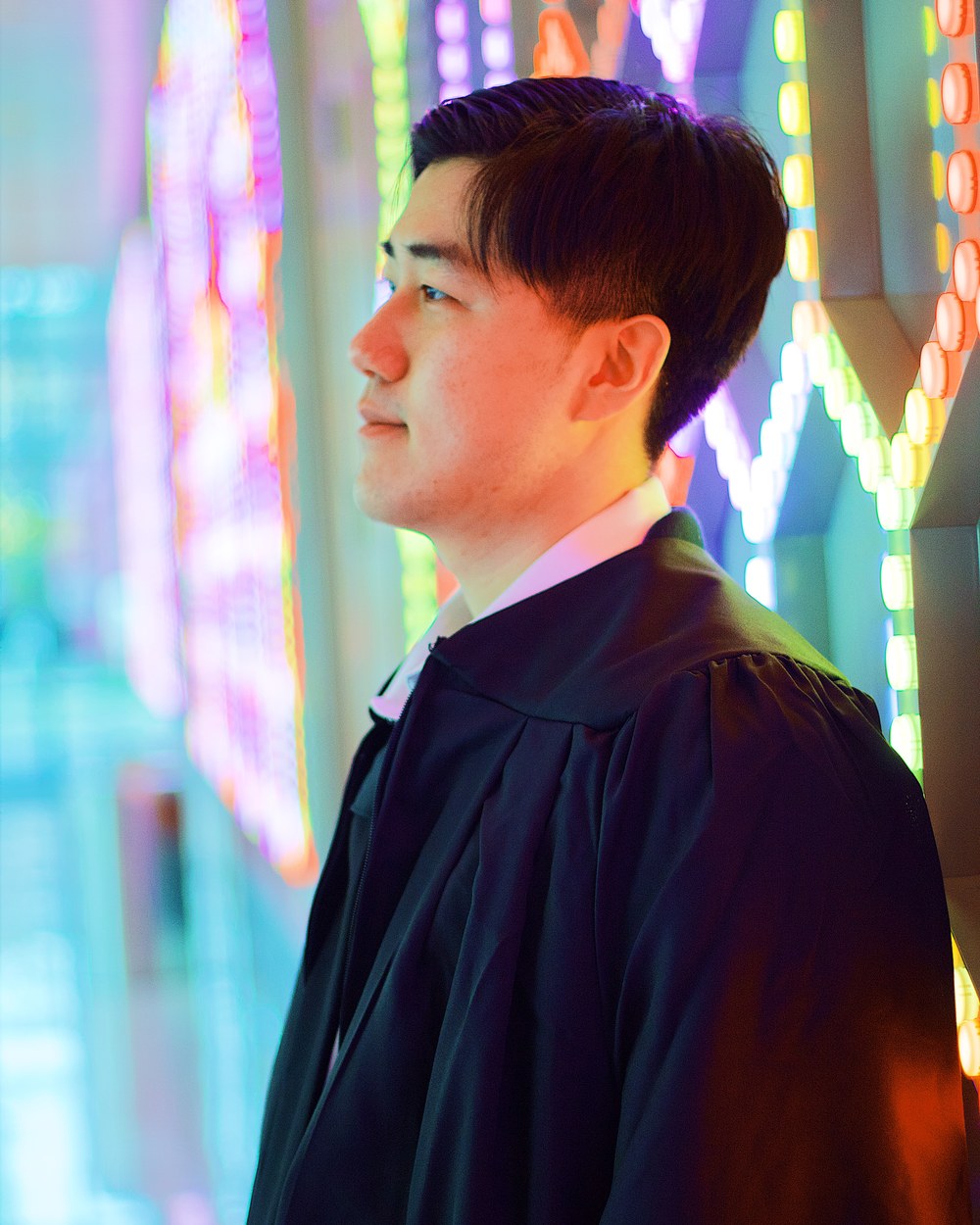 Graduate in profile lit by colored neon light